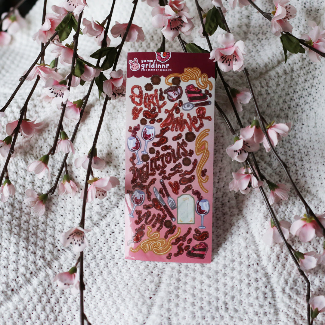 Pack of stickers with food-themed designs on a textured surface with cherry blossoms.